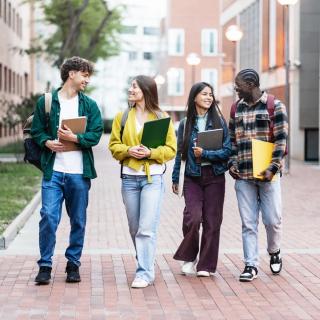 picture of four laughing college students walking together on campus